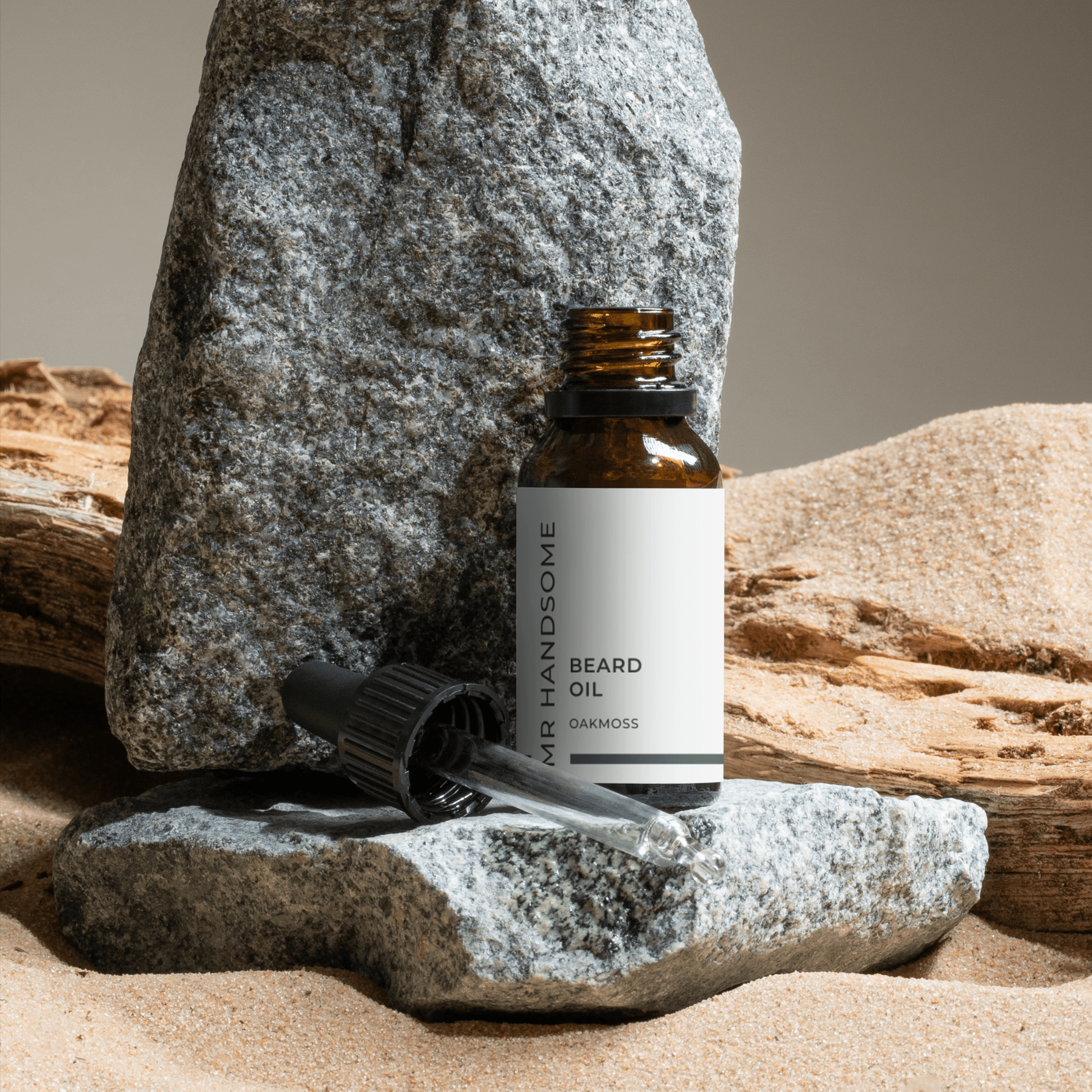 Beard Oil Oakmoss – Tiefenpflege & natürlicher Glanz, Bio-Hanföl & CBD im Fläschchen vor Stein und Sand.