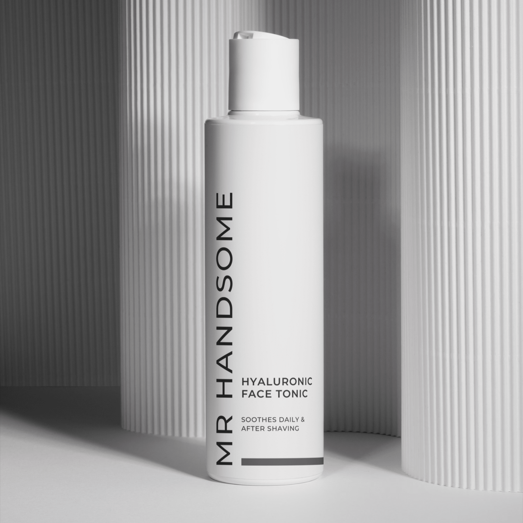 Weiße Hyaluronic Face Tonic Flasche vor geriffeltem Hintergrund, HYALURONIC FACE TONIC Beschriftung sichtbar.