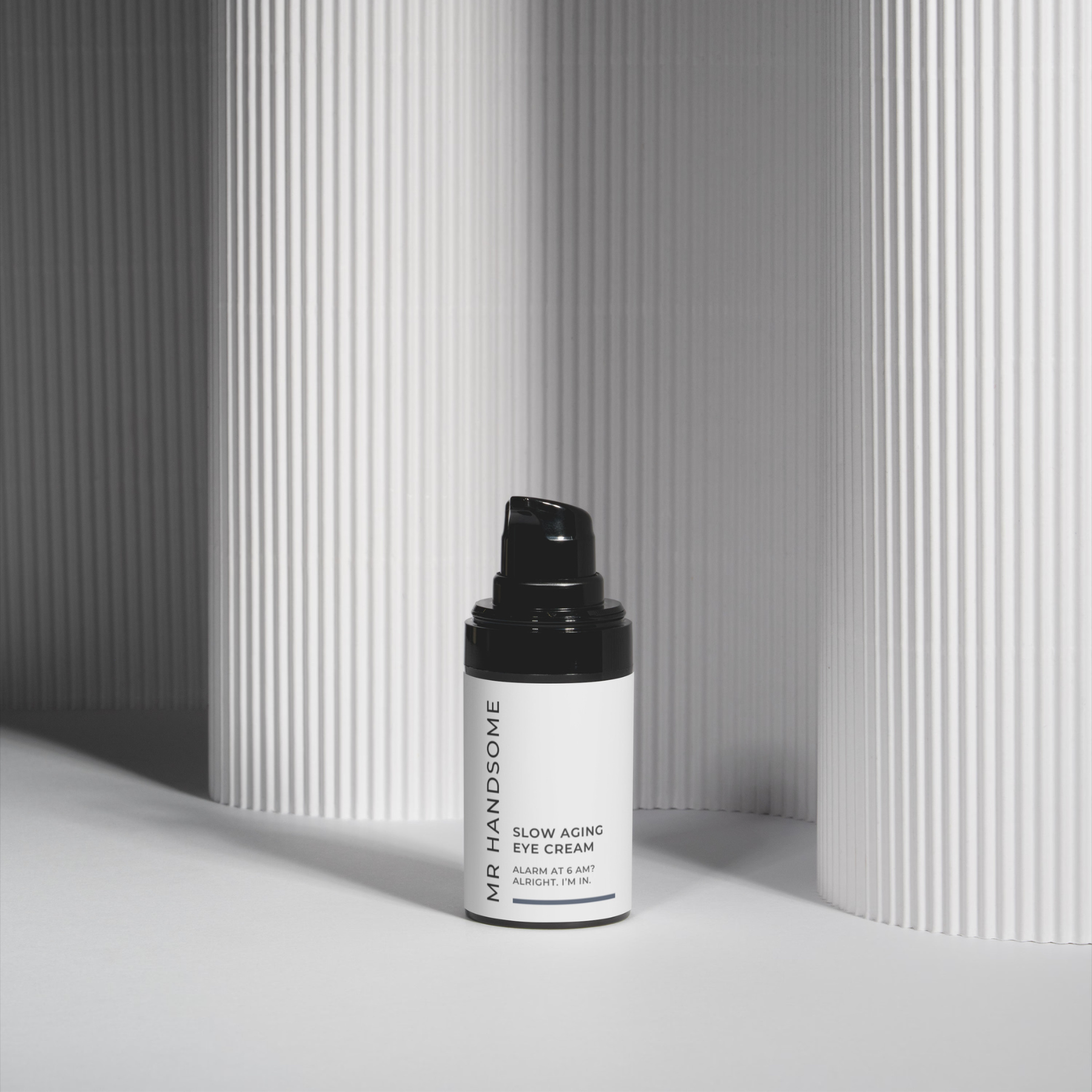 Slow Aging Eye Cream Flasche mit Pumpspender vor silbernem, geripptem Hintergrund.